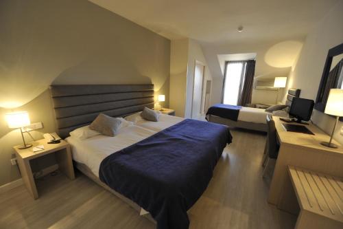 a hotel room with two beds and a desk at Puerta de Segovia in La Lastrilla