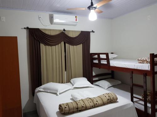 a bedroom with two bunk beds and a ceiling fan at Pousada Sol Nascente ll in Olímpia