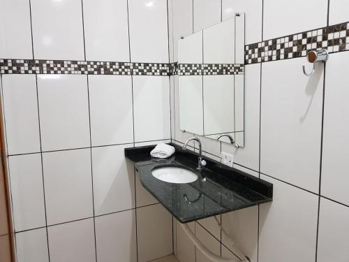 a bathroom with a sink and a mirror at Pousada Sol Nascente ll in Olímpia