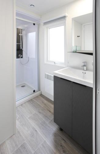 une salle de bain blanche avec un lavabo et une douche dans l'établissement Camping Officiel Siblu La Réserve, à Gastes