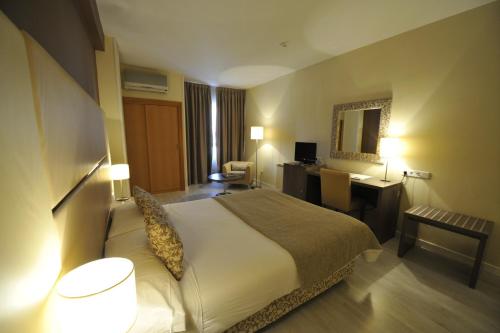 a hotel room with a large bed and a desk at Puerta de Segovia in La Lastrilla