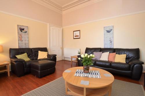 a living room with black leather furniture and a table at Sebright Holiday Apartment in Dunoon