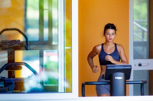 a woman running on a treadmill next to a window at Hotel Marini in Sassari