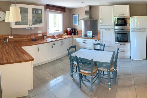 une cuisine avec des armoires blanches et une table et des chaises dans l'établissement Appartement au Coeur de la Provence, à Beaumes-de-Venise