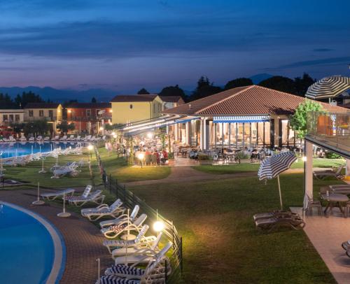 a resort with chairs and a pool at night at Gasparina Village in Castelnuovo del Garda