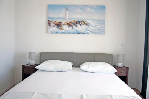 a bed with two pillows and a picture of a lighthouse at Apartments Villa Zvonimir in Slatine