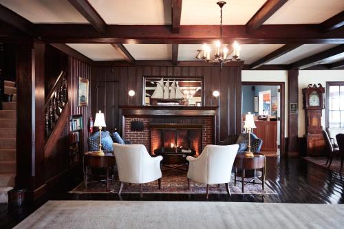 a living room with a fireplace and white chairs at Black Point Inn in Scarborough
