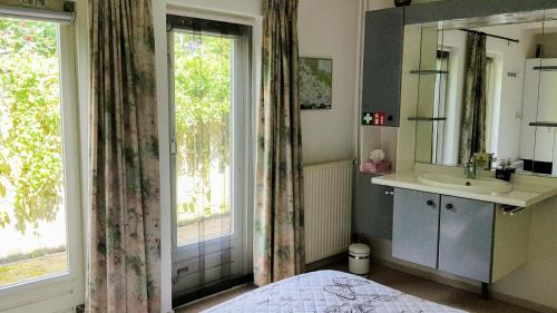 uma casa de banho com uma cama, um lavatório e um espelho. em het Pelikaantje em Werkhoven