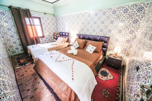 een slaapkamer met 2 bedden in een kamer met behang bij Dar Widad in Ouarzazate