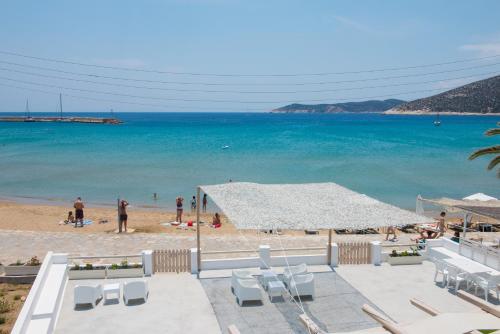una vista di una spiaggia con un ombrellone bianco e sedie di Thalassea Sifnos apartments a Platis Yialos Sifnos