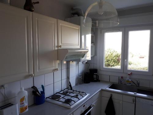 une cuisine avec des armoires blanches et un four à plaques de cuisson dans l'établissement Charmante maison vue mer, à Lestraouen