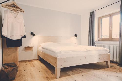 a white bedroom with a bed and a clothes rack at Der Lederer Hof - Boutique Apartments in Tegernsee