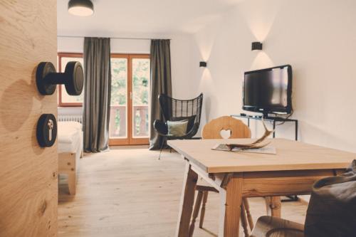 a living room with a tv and a table at Der Lederer Hof - Boutique Apartments in Tegernsee