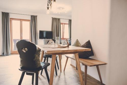 a dining room with a wooden table and chairs at Der Lederer Hof - Boutique Apartments in Tegernsee
