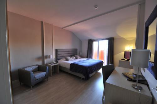 ラ・ラストリージャにあるPuerta de Segoviaのベッドルーム1室(ベッド1台、椅子、デスク付)