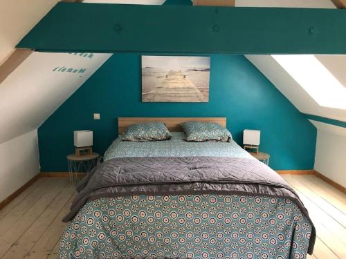 a bedroom with a large bed with a blue wall at Le Fournil - Domaine des Haies in Dol-de-Bretagne