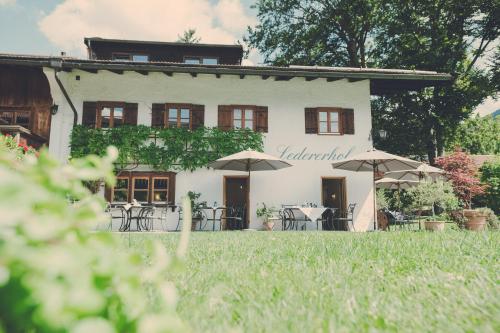 a building with tables and umbrellas in front of it at Der Lederer Hof - Boutique Apartments in Tegernsee