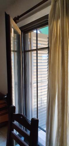 a chair in front of a window with a curtain at Alojamiento Tía Silvia in San José