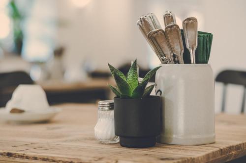 a wooden table with a container with knives and a plant at Der Lederer Hof - Boutique Apartments in Tegernsee
