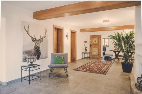a living room with a chair and a painting of a deer at Der Lederer Hof - Boutique Apartments in Tegernsee