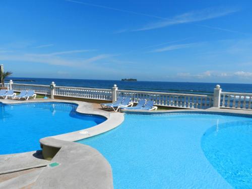 a swimming pool with chairs and the ocean in the background at Astur Hotel & Residence in Veracruz