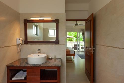 y baño con lavabo y espejo. en Le Tropique Villa, en Grand'Anse Praslin