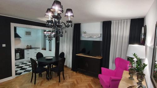 une salle à manger avec une table noire et des chaises roses dans l'établissement Apartament Twarda, à Varsovie