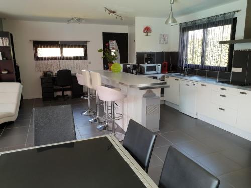 a kitchen with white cabinets and bar stools at VILLA avec piscine chauffée in Moliets-et-Maa