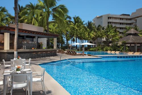 a pool at a resort with a table and chairs at Krystal Grand Nuevo Vallarta in Nuevo Vallarta 