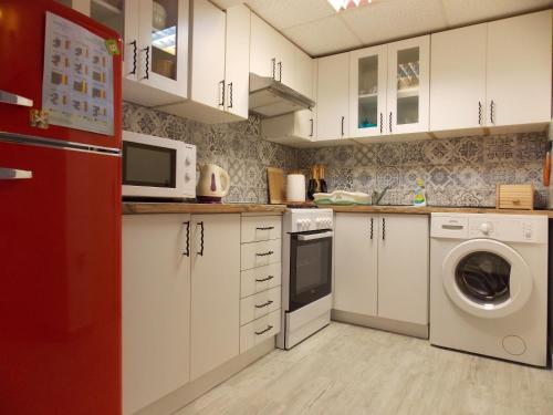 a kitchen with white cabinets and a red refrigerator at Apartment with private garden, hot tub, WiFi, SAT TV, Klima, near beach in Njivice