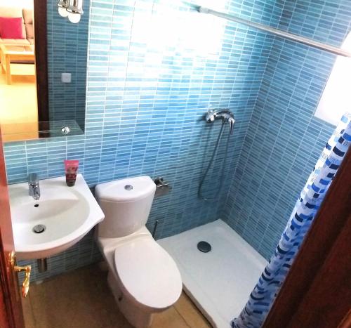 a blue tiled bathroom with a toilet and a sink at Casa Martina in Vejer de la Frontera