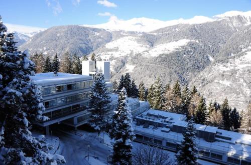 a building in the snow with mountains in the background at Residence Solaria Albarè Marilleva 1400 in Marilleva