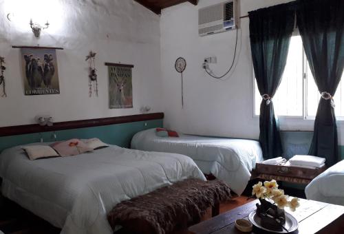 a bedroom with two beds and a table and a window at Hospedaje San Cayetano in Colonia Carlos Pellegrini