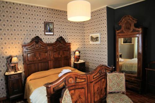 a bedroom with a wooden bed and a mirror at Felicin - Ristorante Albergo "Dimora Storica" in Monforte dʼAlba