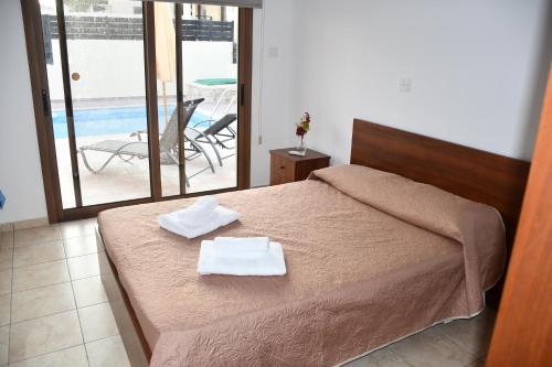 a bedroom with a bed and a view of a pool at Villa Trachonas in Pissouri