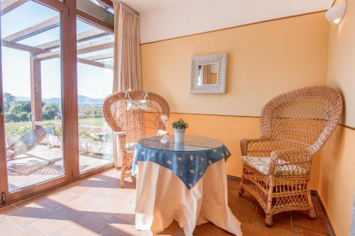 Habitación con mesa, sillas de mimbre y balcón. en Hosteria De Langre, en Langre
