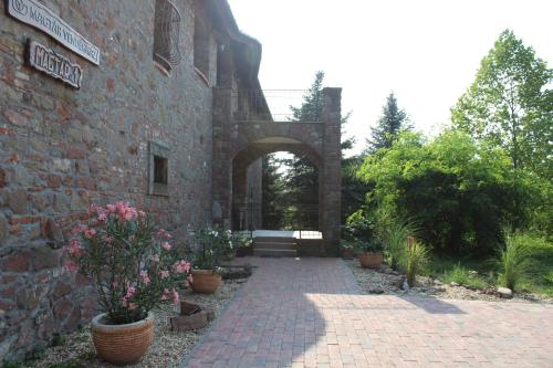 an entrance to a brick building with an arch and flowers at Magtár Vendégház Harsány in Harsány