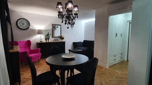 een woonkamer met een tafel en stoelen en een klok bij Apartament Twarda in Warschau