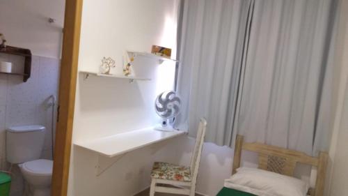 a bathroom with a sink and a toilet and a chair at Alpha Hospedaria & Hostel in Londrina