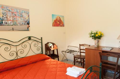 a bedroom with an orange bed with a desk and chairs at Il Covo degli Artisti in Campobello di Licata