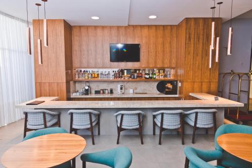 a bar in a restaurant with chairs and a tv at Gran Hotel Morada do Sol in Araraquara