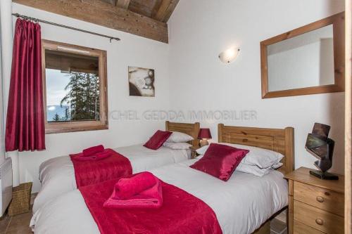 Dos camas en un dormitorio con toallas rojas. en Les Chalets de Wengen - La Panoramique, en Les Coches