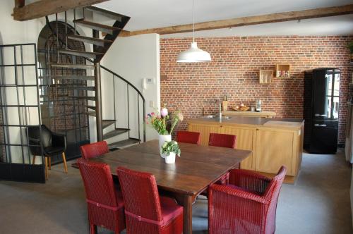 a kitchen with a wooden table and red chairs at Rubbensloft in Zele