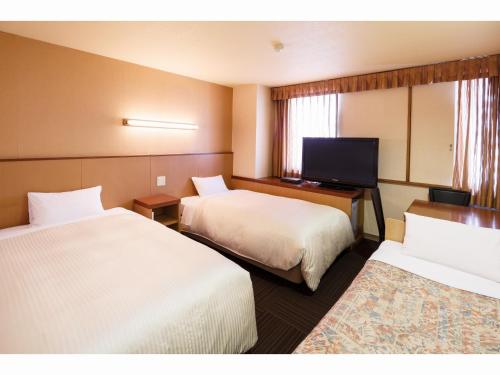 a hotel room with two beds and a flat screen tv at Sunsky Hotel in Kitakyushu