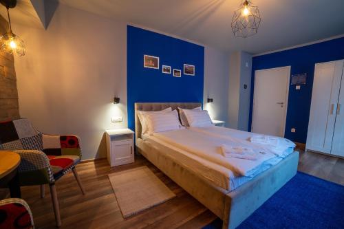 a bedroom with a large bed and a blue wall at Arca Sweet Apartment in Gura Humorului