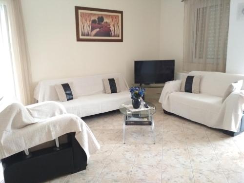 a living room with two white couches and a tv at Eirini in Neochórion
