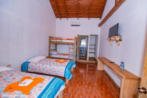 een slaapkamer met 2 bedden en een tv aan de muur bij Linda Vista in Rio Dulce
