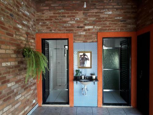 a bathroom with two mirrors and a brick wall at Recanto do Nenê in Botucatu