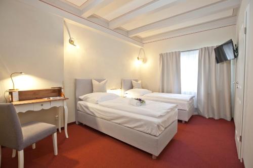 a hotel room with two beds and a chair at Altstadt Gästehaus in Lutherstadt Wittenberg