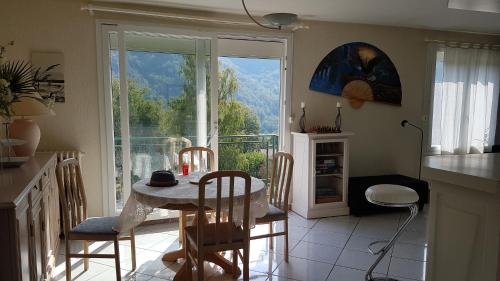 une cuisine avec une table et des chaises ainsi qu'une grande fenêtre dans l'établissement Le Bois Bryas, à Revin
